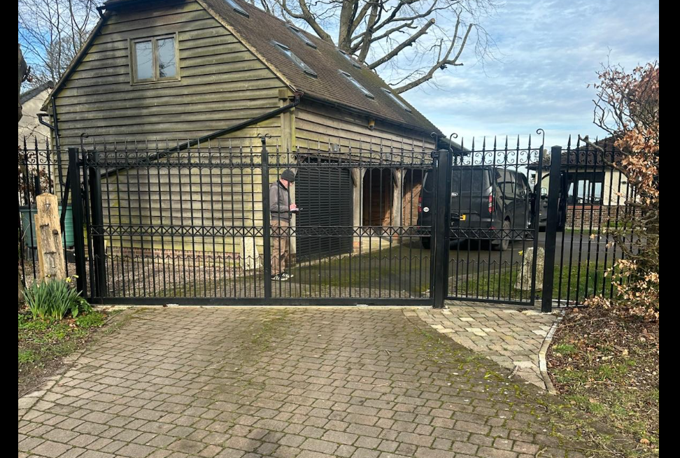 Ornate black wrought-iron sliding gates with scrollwork detail.