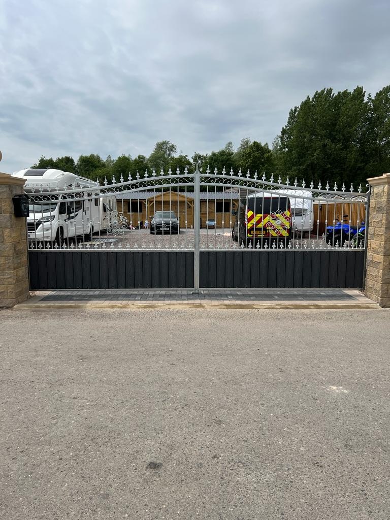 Galvanised silver arched driveway gates with dark composite infill.