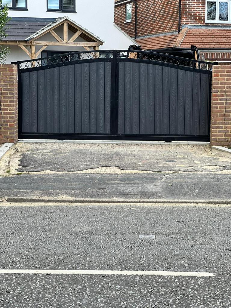 Arched black gates with grey vertical composite infill panels.