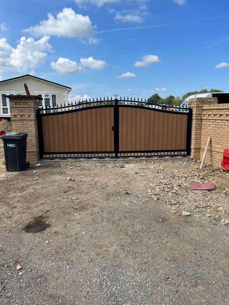 Arched black steel gates with horizontal composite panels between brick pillars.