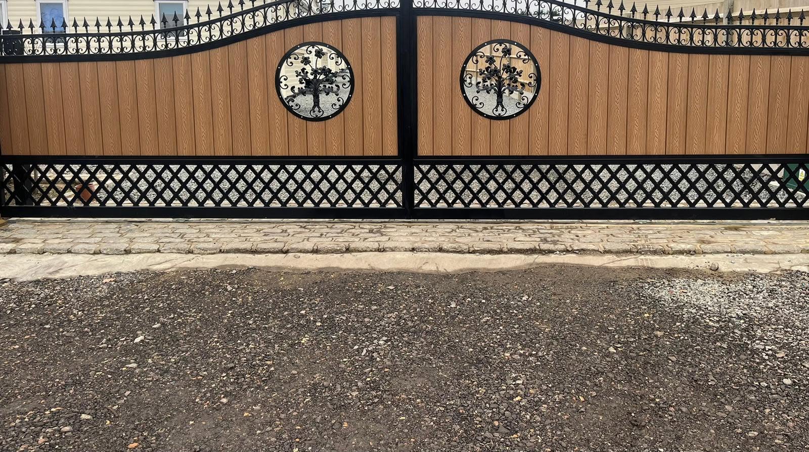Ornate black wrought-iron gates with tree-of-life medallions and wood-effect composite infill.