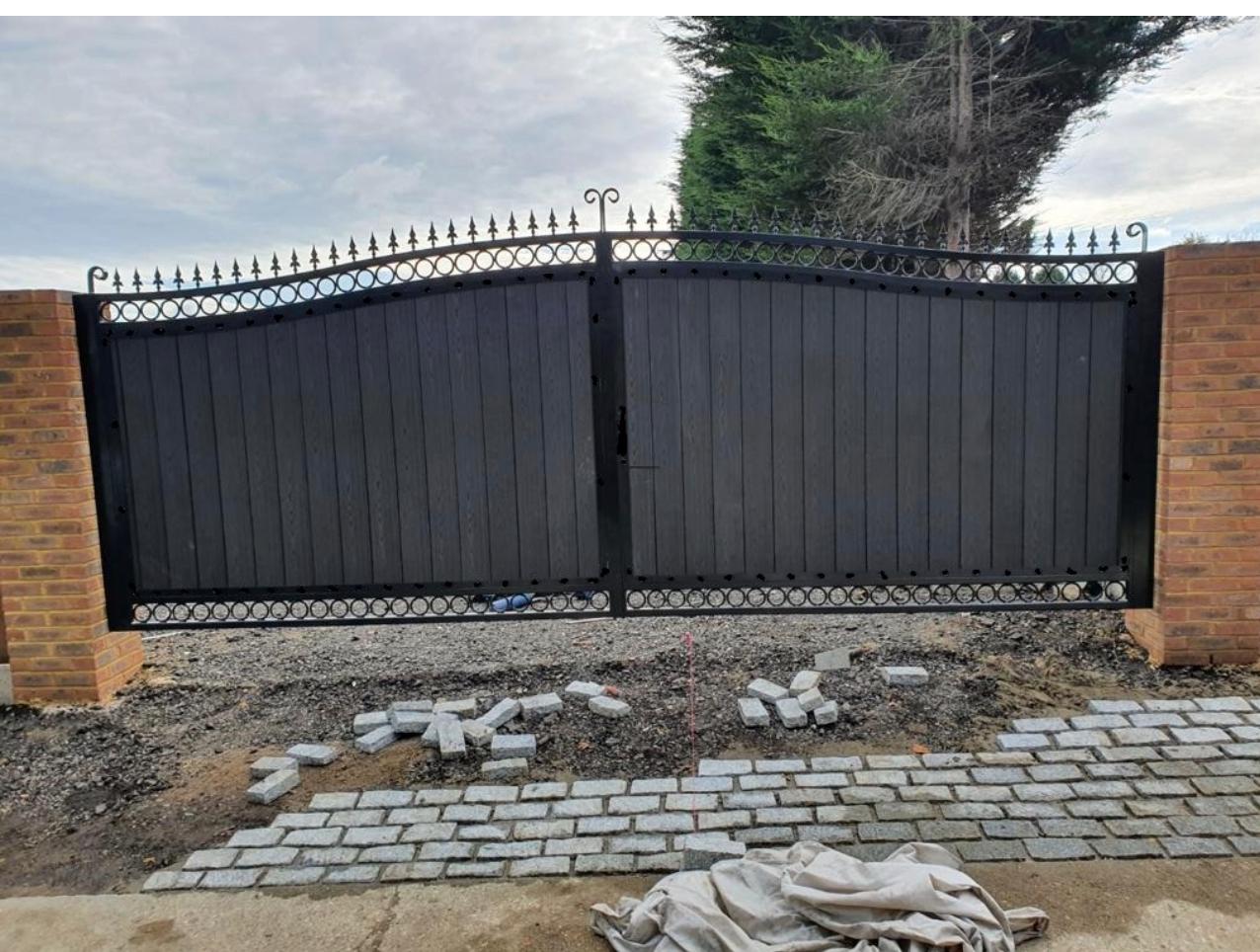 Large arched black driveway gates with composite infill under fitting.