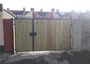 Black steel-framed double driveway gates with timber infill and decorative finials.